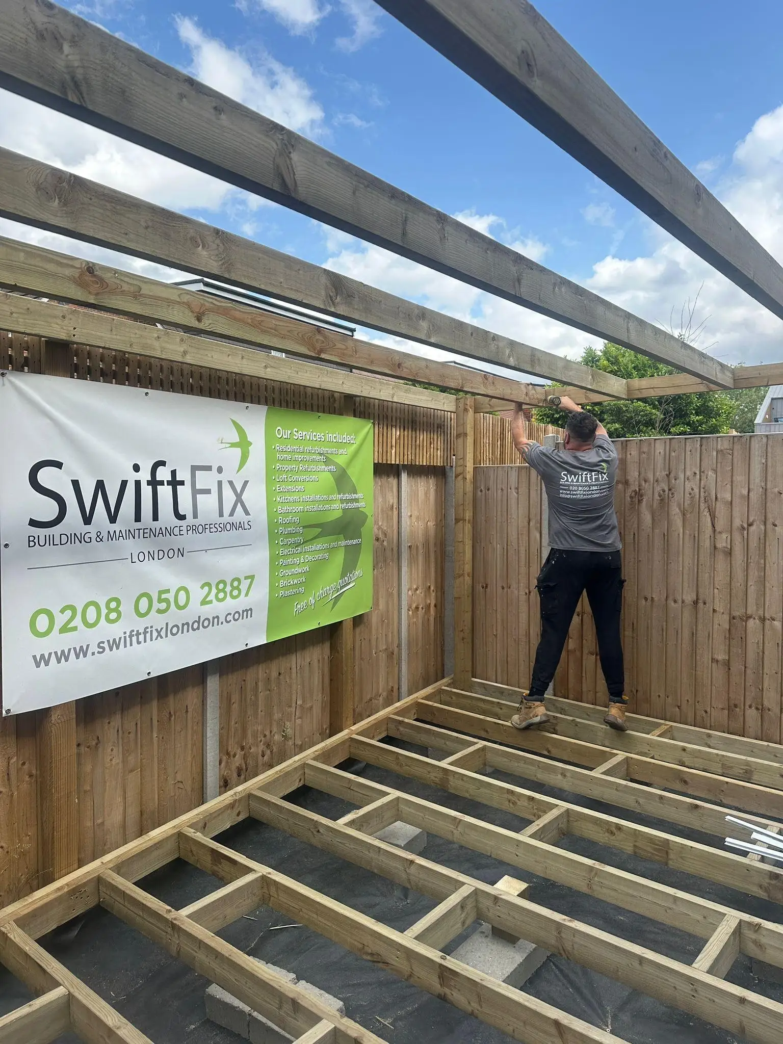 Timber decking sub-frame under construction with Swift Fix banner on the fence