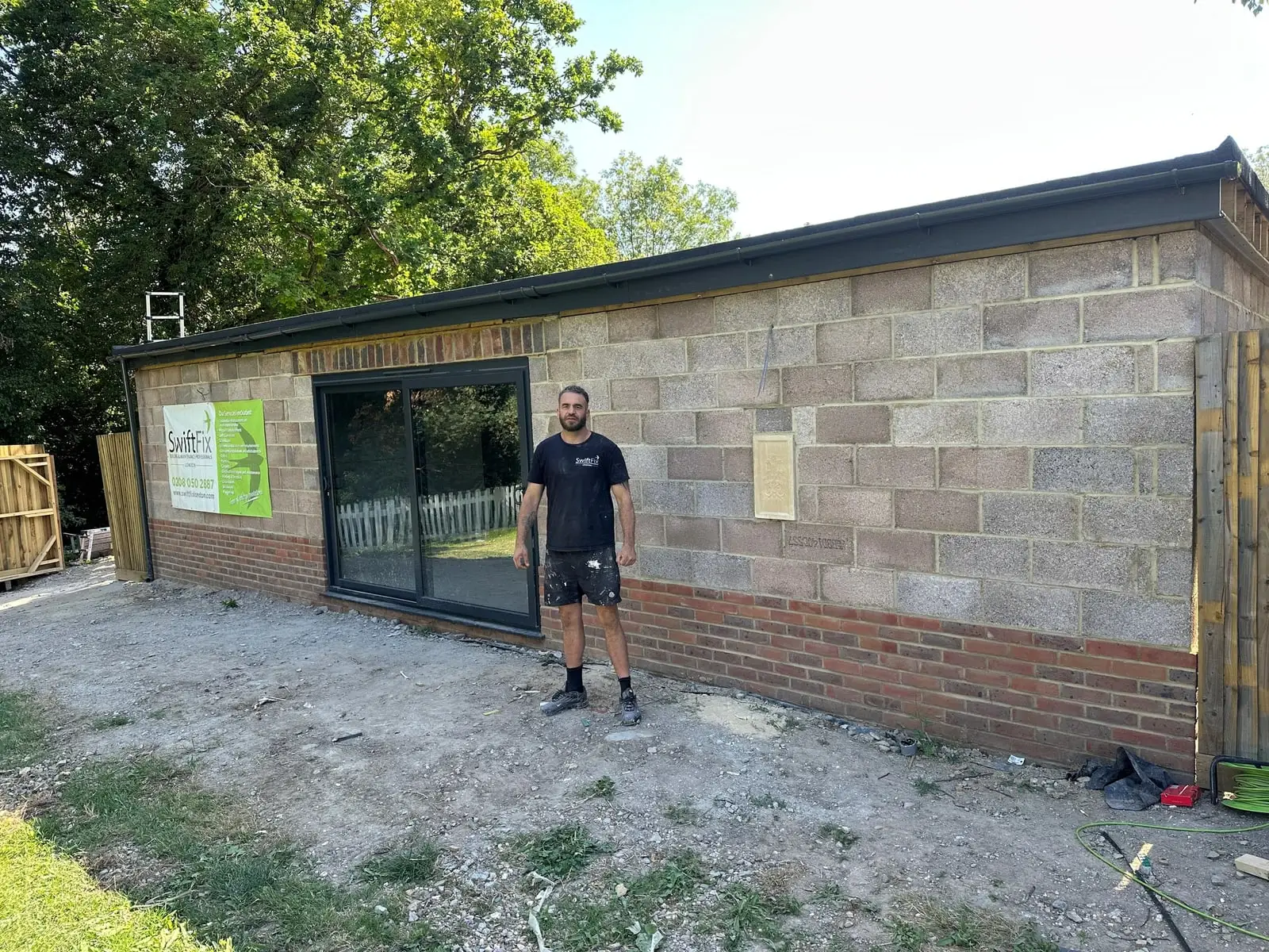 Garden gym outbuilding built in blockwork with sliding glazed doors and a Swift Fix banner