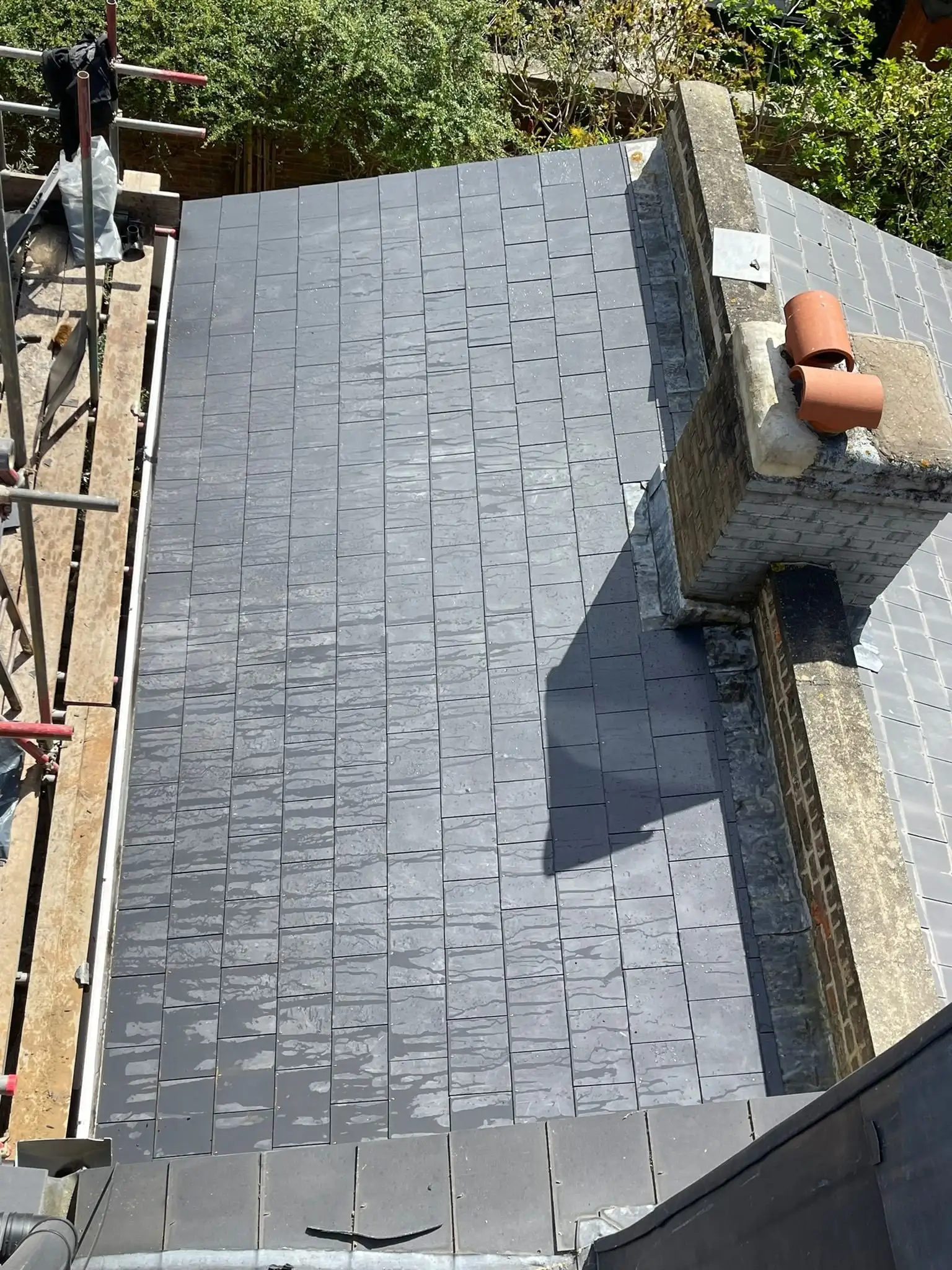 Completed slate re-roof running up to a brick chimney stack in London