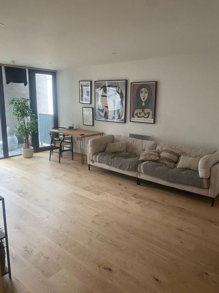  Home Renovations in Haringey - Open-plan living space renovated by SwiftFix London with wooden floors, beige sofa, dining area, and wall art.