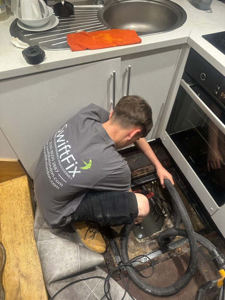 Skilled tradesmen in Wandsworth - a plumber working to fix a blockage in kitchen 